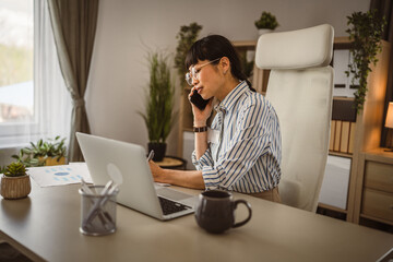 Wall Mural - Mature japanese woman with eyeglasses talk on phone at the office