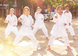 Multiracial group of concentrated preteen children practicing karate movements during outdoors group class on summer city street