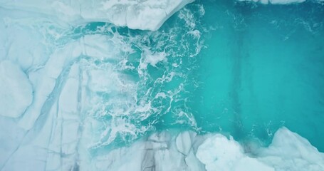 Wall Mural - Glacier surface melting blue water washed by ocean waves. Aerial view frozen crystal ice lake. Melting icy glacier cave. Snow covered formation in Antarctica. Global warming climate change. Top down