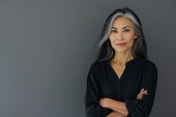 Stylish confident adult 50 years old Asian female psychologist standing arms crossed looking at camera at gray background. Portrait of sophisticated grey hair woman advertising product - generative ai