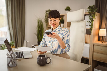 Wall Mural - Mature japanese businesswoman with eyeglasses scan document at the office