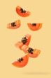 Falling papaya slice on light orange background.