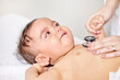 © peopleimages.com - Sick baby, scared and doctor hands with stethoscope for check up, healthcare and illness in family clinic. Child, female physician and hospital bed for sad kid, medical aid and pediatrician