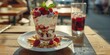 Delicious summer parfait with fresh raspberries and creamy yogurt on sunlit wooden table, refreshing drink beside, perfect for warm days.