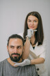 © Anna - Portrait of a young beautiful woman beautician in a medical white uniform and a young bearded man patient