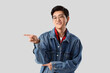 © Pixel-Shot - Young Asian man pointing at something on light background