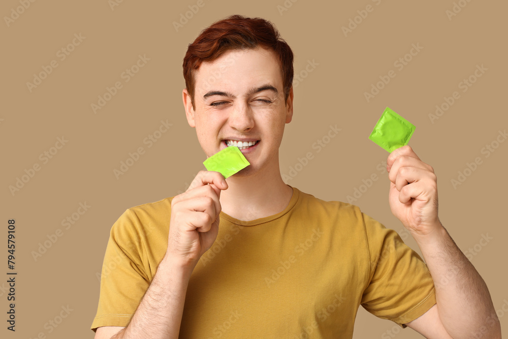 Young man with condoms on beige background. Safe sex concept