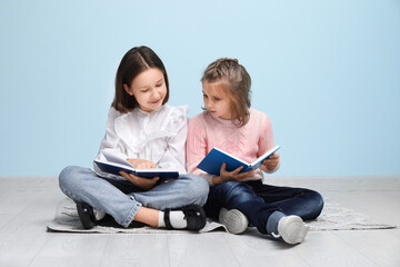 Sticker - Little children reading books while sitting on floor near blue wall