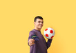 © Pixel-Shot - Young man with soccer ball and credit cards on yellow background