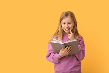 Canvas Print - Cute little girl with book on yellow background