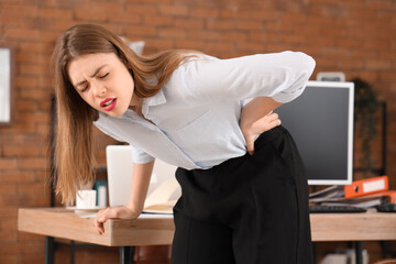 Wall Mural - Beautiful businesswoman suffering from back pain in office