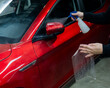A technician sprays water before applying protective vinyl film to a car.