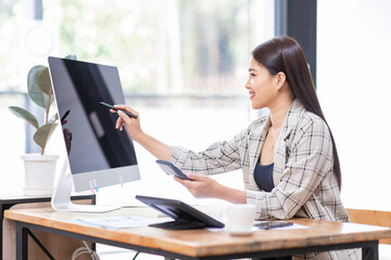 Young happy professional business asian woman employee sitting at desk working on laptop in modern corporate office interior. Smiling female worker using computer technology typing browsing web.