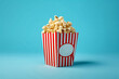 Crunchy popcorn snack in a red and white stripline paper box placed on a red floor of a movie theater or cinema for commercials. Generative AI.