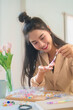Young asian women stringing beads on thread and choosing colorful beads from box to making handmade bracelet while spending time to creating jewelry handicraft and doing hobby lifestyle at home