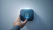 A hand is setting a smart home thermostat to 26 degrees Celsius, a step towards energy-efficient home management.
