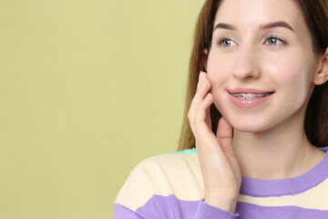 Poster - Portrait of smiling woman with dental braces on light green background. Space for text