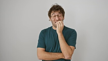 Sticker - Stressed young hispanic man, wearing glasses, biting nails, looking nervous, exhibits anxiety problem, standing isolated against white background