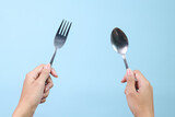 Fototapeta  - Woman hands holding spoon and fork isolated on blue background