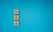 Wooden blocks with numbers 1, 2, and 3 on a blue background.