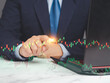 Hand of a businessman pointing at graph stock on a virtual screen.