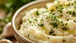 A closeup of a bowl filled with creamy mashed potatoes, garnished with a generous sprinkle of fresh parsley