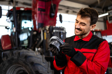 Poster - Professional mechanic servicing tractor gears transmission inside workshop.