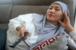 © Hendra Fauzy - Asian muslim woman in hijab, laying on sofa and enjoying watching tv at home