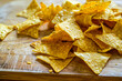 A pile of tortilla chips on a wooden cutting board