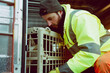 Worker in High-Visibility Jacket Checking Dog in Transport Crate