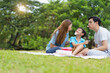 © DG PhotoStock - Happy cheerful Asian family with father, mother, and little son enjoy picnic together in a weekend at a park. Happy family moment concept. Parent and their child relax together in the park.