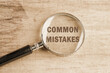 Common mistakes, text visible through a magnifying glass on an old faded background