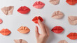 Finger touching a red paper origami lip among many on a white background.