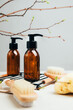 Set of natural cosmetics. Amber bottles with facial, bath liquid on a concrete background with young twigs of a tree. Front view
