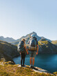 Couple hikers man and woman with backpack hiking in mountains together exploring Norway healthy lifestyle outdoor active family vacations adventure tour, friends enjoying lake view in Lofoten islands