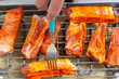 Turning pieces of pork on electric barbecue with a fork