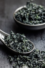 Wall Mural - Dried wakame seaweed in spoon on black table.