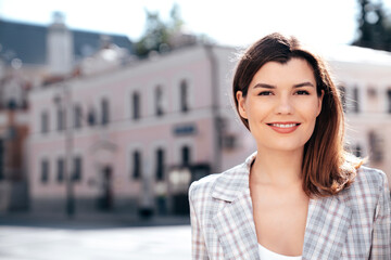 Wall Mural - Portrait of young beautiful brunette woman wearing nice trendy plaid suit jacket. Sexy smiling model posing in the street at sunny day. Fashionable female outdoors. Cheerful and happy.