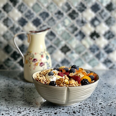 Muesli in a Bowl with a Jug of Yogurt on a Silver Speckled Surface