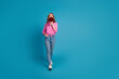 Full body photo of pretty young girl hold megaphone walking wear trendy pink outfit hairdo isolated on blue color background