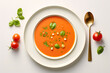 Plate of gazpacho on white background with tomatoes and mint