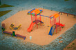 Aerial view of childrens playground at park. Run slide swing sand carousel on modern colorful children playground on yard activities in public outdoor surrounded by cobble stone at sunlight morning