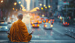 A man in a yellow robe is sitting on a ledge in the middle of a busy city street