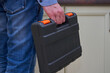 a man holds a toolbox, close-up of a man in jeans and a case of tools for repairing furniture in the kitchen, repairman at home