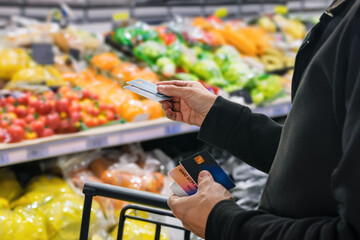 Wall Mural - Male customer paying for groceries at supermarket using his credit card. Seamless checkout: Payment cards offer ease and convenience at the supermarket