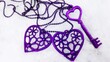 Two violet hearts and key on white snow connected by metal chain. Love friendship romantic couple concept valentine day. Trinket or pendant in heart shape for lovers pattern background or card texture