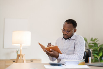 Wall Mural - African American businessman working with documents, taking notes in the office, preparing a performance analysis report.