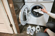 Cropped photo of woman putting her shoes to washing machine. Sport shoes need to be washed after long workout outdoor.