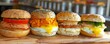 A variety of breakfast sandwiches on a wooden table including lox, egg and cheese, and bacon, egg and cheese.