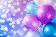 Bunch of colorful helium balloons floating on colorful bokeh background.